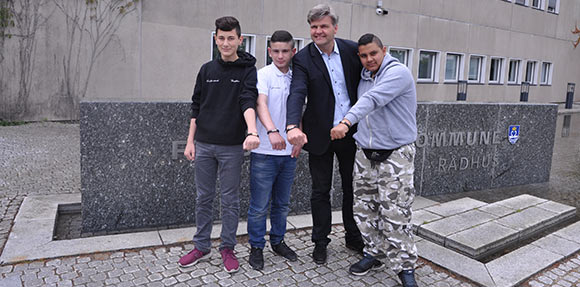 Borgmester i Fredensborg Kommune Thomas Lykke Pedersen  fik overrakt et sort læderarmbånd med metalspænde. Her er han foran rådhuset sammen med, fra venstre 14-årige Eren, 14-årige Mohammed  og 15-årige Ibrahim. Foto: Fredensborg Kommune